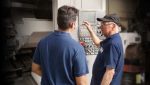 manufacturer working at CNC with trainee